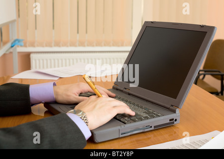 Il laptop e mani dell'uomo con una penna Foto Stock