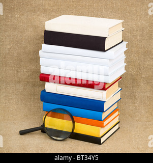 Libri e lente di ingrandimento sullo sfondo del tessuto Foto Stock