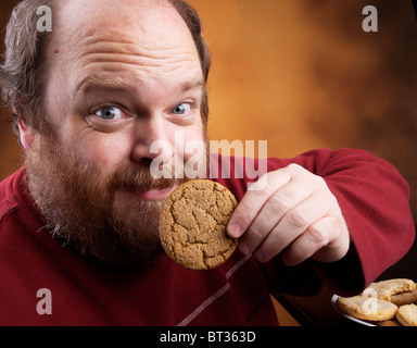 Il sovrappeso uomo di mezza età con i cookie Foto Stock