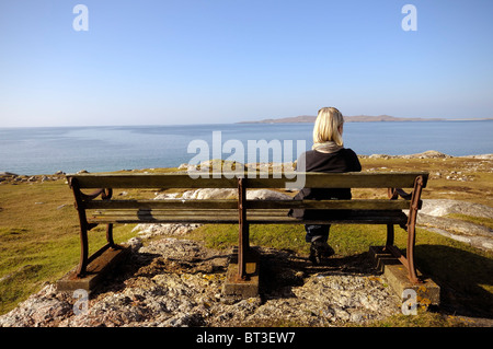 Donna seduta su una panchina affacciata sul mare Foto Stock