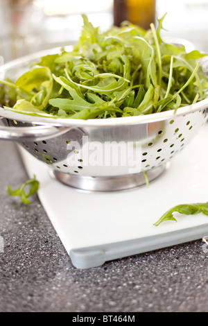 Foglie di rucola fresca (rucola) in un colino, pronte per essere aggiunte a un'insalata Foto Stock