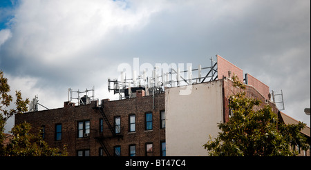 Un telefono cellulare trasmettitore farm si trova sul tetto di un palazzo di appartamenti in New York quartiere di Harlem Foto Stock