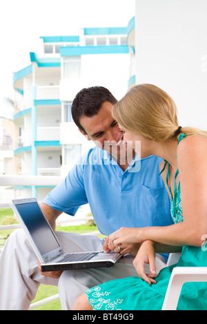 Felice coppia giovane utilizzando computer portatile sul balcone Foto Stock
