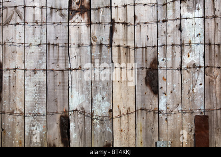 Staccionata in legno intrecciate da un filo spinato Foto Stock