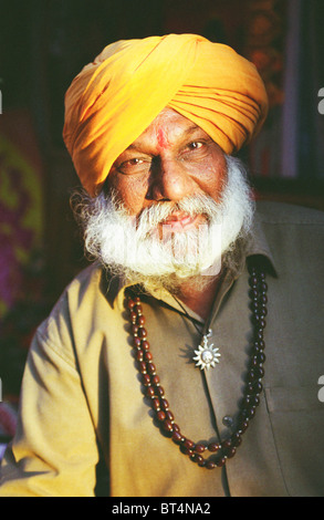 Indian uomo ritratto di un pittore al market shop in Puskar Rajasthan in India. Indossare golden turbante giallo. Foto Stock