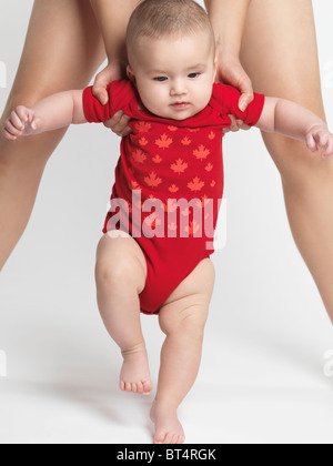 Bambino di quattro mesi boy cercando di camminare con madre di aiuto Foto Stock