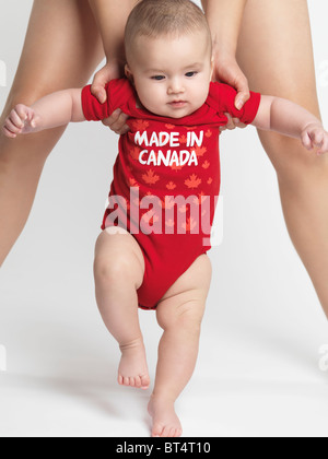 Bambino di quattro mesi boy cercando di camminare con madre di aiuto Foto Stock