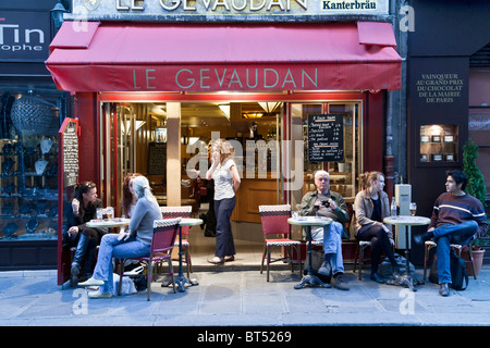 Diversi giovani francesi e un senior American uomo seduto in un momento di relax a posti a sedere esterni piccolo cafè sul marciapiede di Rue du Bac a Parigi Foto Stock