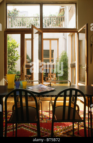 Townhouse sala da pranzo con sedie nere e la tabella nella parte anteriore di aprire finestre Francesi al piccolo cortile Foto Stock