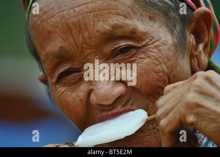 Donna anziana dal fiore tribù Hmong mangiare un gelato, SAPA, Vietnam Foto Stock