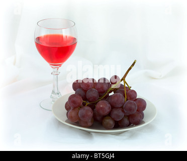 Still-life con un bicchiere di vino rosso e Uva su sfondo bianco Foto Stock