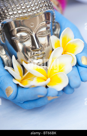 Ragazza indiana con lancette blu tenendo un buddha d'argento e fiori di frangipani Foto Stock