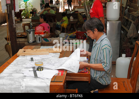 Un motivo designer uomo progettazione di mobili in legno di teak incisione. Bangkok, Thailandia, Settembre 2010 Foto Stock