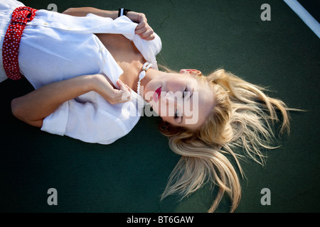 Ragazza che stabilisce tenendo il suo collare della camicia che guarda lontano Foto Stock