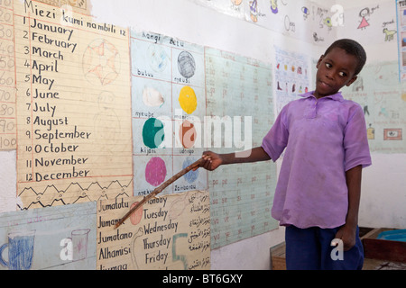 Jambiani, Zanzibar, Tanzania. Giovane studente punti per i nomi dei giorni della settimana in lingua Swahili. Foto Stock