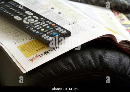 Telecomando TV seduti sulla parte superiore dei televisori riviste sul braccio di una sedia Foto Stock