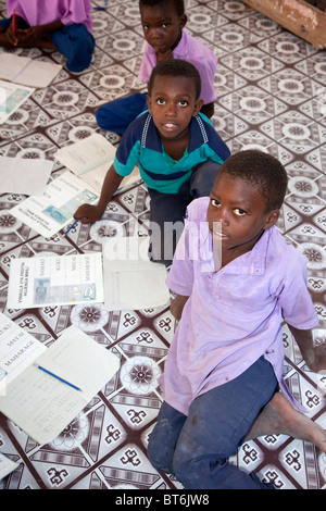 Jambiani, Zanzibar, Tanzania. I ragazzi della scuola primaria. Gli studenti seduti sul pavimento dal momento che la scuola non ha alcun mobili. Foto Stock