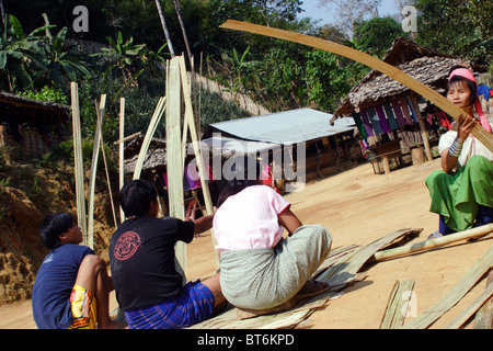 Karen Paduang giraffa rifugiati provenienti dalla Birmania (Myanmar) sono la realizzazione di un tetto di paglia in Ban Nai Soi, Thailandia. Foto Stock