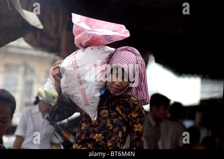 Una donna Khmer è portatore di un grande e pesante sacco di riso sulla sua spalla vicino al mercato principale di Kampong Cham, Cambogia. Foto Stock