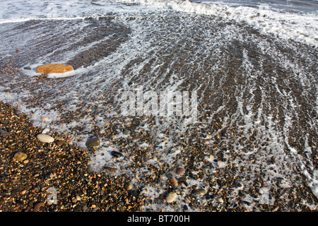 Il surf e la laminazione delle onde sulla riva sabbiosa off Northumberland coast. Foto Stock