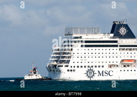 Andando ocean liner grande nave da crociera Barca barche rimorchiatore rimorchiatore a traino il lusso di essere guidato nel Port Harbour spingere spinto grandi docking dock Foto Stock