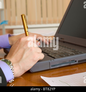 Il laptop e mani dell'uomo con una penna Foto Stock