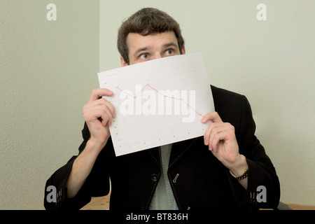 Direttore su un posto di lavoro con un grafico in una mano Foto Stock