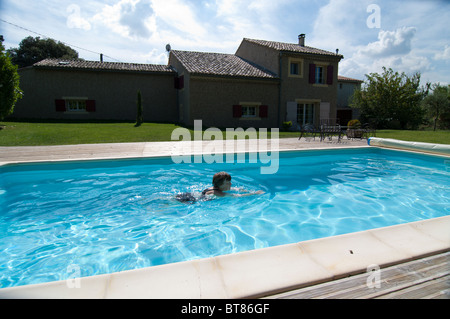 Persona ha una piscina a se stessi con la casa vacanze in background Foto Stock