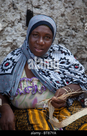 Jambiani, Zanzibar, Tanzania. Donna che fa una cinghia da un intreccio di erba. Foto Stock