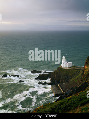 Faro di Hartland Point sulla costa nord del Devon vicino a Hartland, Inghilterra. Lundy Island è visibile all'orizzonte nella nebbia. Foto Stock