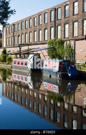 Barche ormeggiate accanto al vecchio edificio del mulino, Ashton canal, Ashton Under Lyne, Tameside, Greater Manchester, Inghilterra, Regno Unito Foto Stock