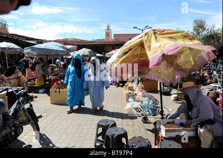 Donne islamiche in abito tradizionale a piedi attraverso il luogo di mercato Djemaa El Fna a Marrakech. Foto Stock