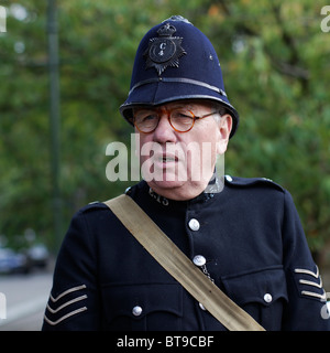 Quaranta anni di guerra British Bobby sergente di polizia in abbottonato tunica blu con manicotto insegne & custode casco Foto Stock