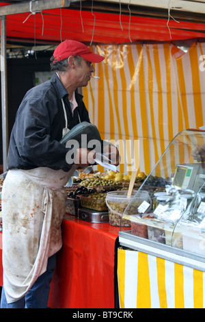 Uomo in un mercato di vendita di stallo olive a Parigi, Francia Foto Stock