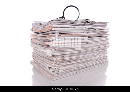 Ingrandire il vetro sopra una pila di giornale per trovare informazioni fresche (isolato su bianco) Foto Stock