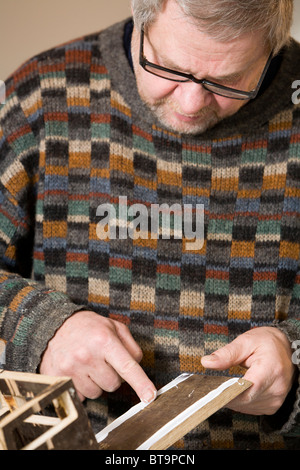 Uomo che fa un giocattolo di legno carrello. Foto Stock