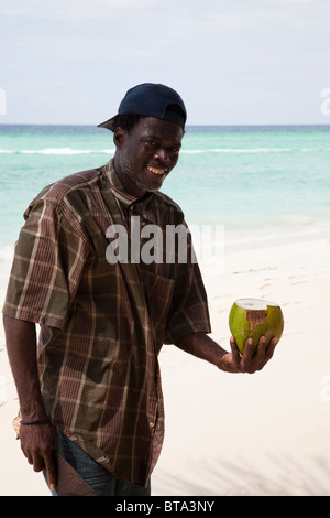 Local uomo nero con machete taglio noci di cocco fresco in modo tale che egli può vendere il latte. Barbados. Indie occidentali Foto Stock