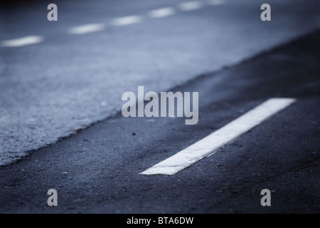 Linee bianche su una vecchia strada. Reparto poco profonda del campo. Foto Stock