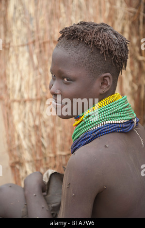 Nyangatom (Bumi) ragazza con pile di perle nella parte anteriore del suo rifugio, Omo river Valley, Etiopia Foto Stock