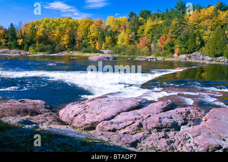 Alberi colorati e rocce al fiume Mississagi e rapide in autunno vicino al fiume cieco sull'autostrada #17 in Ontario, Canada Foto Stock