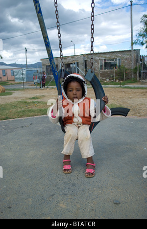 Una bambina gioca su una oscillazione in un Zola township, Somerset West vicino a Cape Town, Sud Africa. Foto Stock