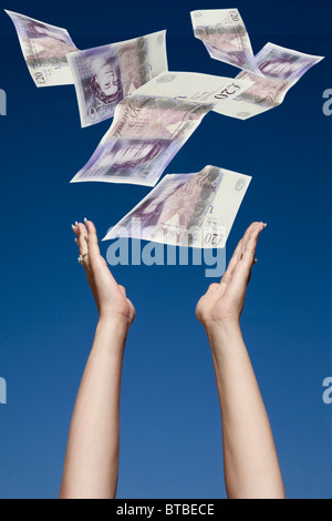 Womans mani stretching fino a un massimo di catture £20 rileva la caduta da un cielo blu Foto Stock