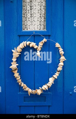 A forma di cuore ad seashell appendere decorazione su un blu porta in legno nel Regno Unito Foto Stock