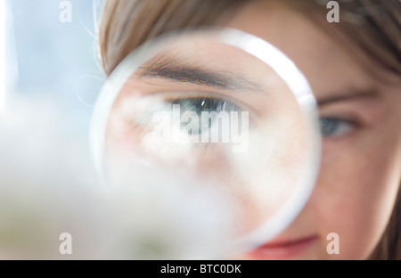 Giovane ragazza guardando attraverso la lente di ingrandimento Foto Stock