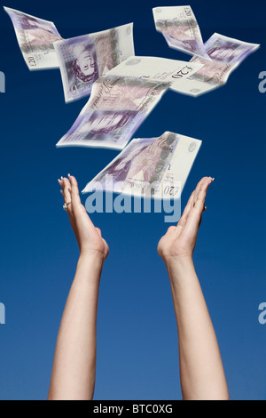 Womans mani stretching fino a un massimo di catture £20 rileva la caduta da un cielo blu Foto Stock