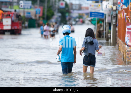 Coppia giovane guadare attraverso le strade della città durante il monsone peggiore alluvione in 50 anni Foto Stock
