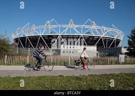 Due ciclisti passare il in parte costruito Londra 2012 Olympic Athletics Stadium di Stratford, a est di Londra. Ott 2010 Foto Stock