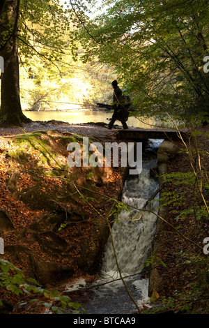 Fisherman attraversando ponte pedonale tra due laghi Foto Stock