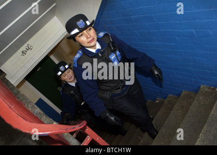 Comunità femminile di supporto degli ufficiali di polizia a camminare su una scala in un blocco di appartamenti in Londra Sud, Regno Unito Foto Stock