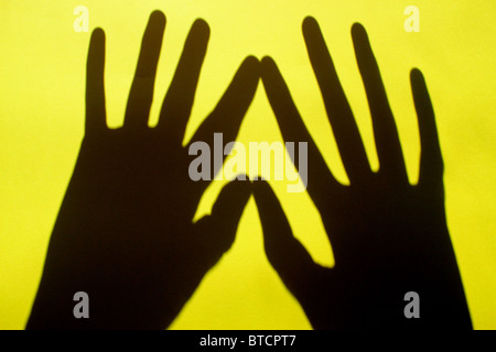 Due ombre a mano toccare su un brillante sfondo giallo Foto Stock